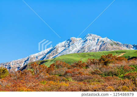Mount Chokai, Yamagata - White snow-capped summit and autumn foliage at the base - 125486979