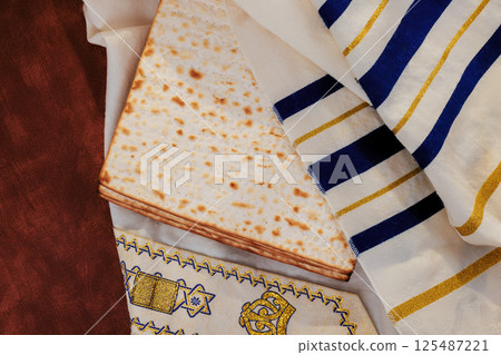 Matzah rests atop beautifully designed tallit prayer shawl, symbolizing traditions during Passover holiday. 125487221