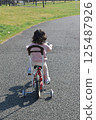 Child riding a bicycle with training wheels 125487926