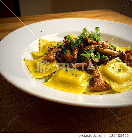 Yellow ravioli pasta with sauteed chanterelle mushrooms and fresh herbs on a white plate 125488465