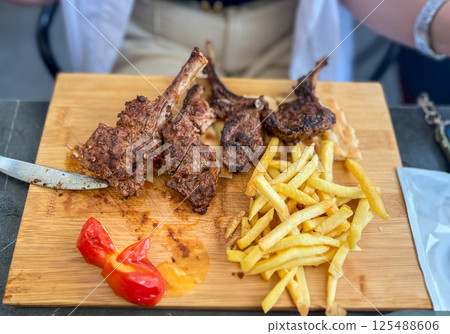 Grilled lamb chops with french fries and vegetables on a wooden board Grilled lamb chops with french fries and vegetables on a wooden board 125488606