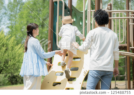 Parents and children playing on a slide in the park. No smiling child's face. 125488755