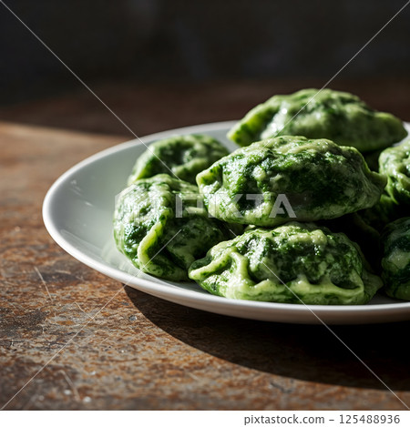 Green dumplings on a white plate on a wooden surface 125488936