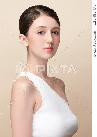 A beautiful young woman with clean, fresh skin against a beige background. Skincare, facial treatment, cosmetology, beauty, and spa. An elegant portrait of an woman. A beautiful young woman with clean, fresh skin against a beige background. Skincare, facial treatment, cosmetology, beauty, and spa. An elegant portrait of an woman. 125489479