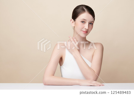A beautiful young woman with clean, fresh skin against a beige background. Skincare, facial treatment, cosmetology, beauty, and spa. An elegant portrait of an woman. A beautiful young woman with clean, fresh skin against a beige background. Skincare, facial treatment, cosmetology, beauty, and spa. An elegant portrait of an woman. 125489483