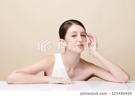 A beautiful young woman with clean, fresh skin against a beige background. Skincare, facial treatment, cosmetology, beauty, and spa. An elegant portrait of an woman. A beautiful young woman with clean, fresh skin against a beige background. Skincare, facial treatment, cosmetology, beauty, and spa. An elegant portrait of an woman. 125489489