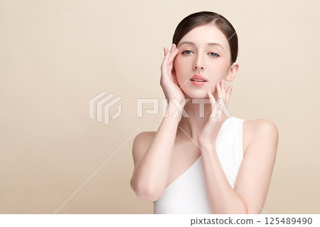 A beautiful young woman with clean, fresh skin against a beige background. Skincare, facial treatment, cosmetology, beauty, and spa. An elegant portrait of an woman. A beautiful young woman with clean, fresh skin against a beige background. Skincare, facial treatment, cosmetology, beauty, and spa. An elegant portrait of an woman. 125489490