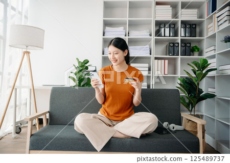 Asian woman hands using smartphone and holding credit card sitting. Online Shopping payments concept. 125489737