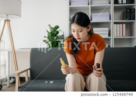 Asian Woman sitting in the sofa with a large number of pills Depressed woman wants to kill herself by drug overdose, depression concept. 125489749