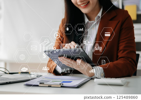Designer woman using smart phone for mobile payments online shopping sitting on table,virtual icons Designer woman using smart phone for mobile payments online shopping sitting on table,virtual icons 125489860