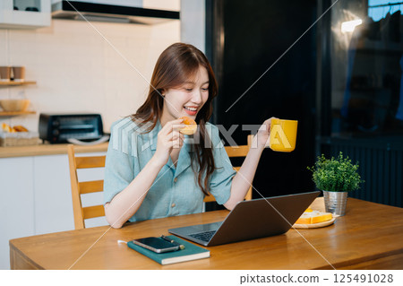 Lifestyle people, Happy woman enjoys breakfast sitting in the kitchen. Lifestyle people, Happy woman enjoys breakfast sitting in the kitchen. 125491028