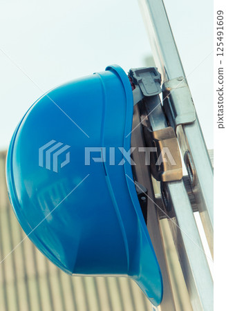 Protective blue helmet on aluminum ladder. Safety at work Protective blue helmet on aluminum ladder. Safety at work 125491609