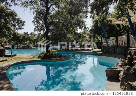 An elegant tropical resort with shady gardens and a winding pool surrounded by greenery. Turquoise water and a warm atmosphere of relaxation. An elite resort complex with crystal clear water. An elegant tropical resort with shady gardens and a winding pool surrounded by greenery. Turquoise water and a warm atmosphere of relaxation. An elite resort complex with crystal clear water. 125491938