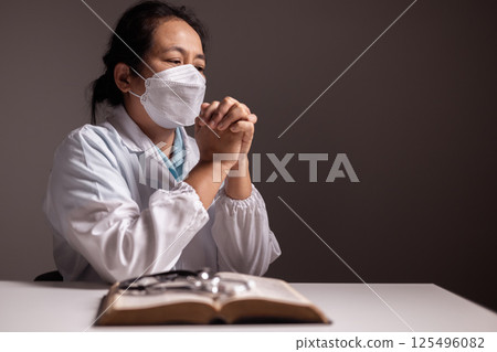 Woman prays with her hands clasped, believing in the care of doctors and medical professionals as she faces disease in a hospital or clinic, trusting in the strength of health care. doctor, disease. Woman prays with her hands clasped, believing in the care of doctors and medical professionals as she faces disease in a hospital or clinic, trusting in the strength of health care. doctor, disease. 125496082