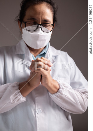 Woman prays with her hands clasped, believing in the care of doctors and medical professionals as she faces disease in a hospital or clinic, trusting in the strength of health care. doctor, disease. Woman prays with her hands clasped, believing in the care of doctors and medical professionals as she faces disease in a hospital or clinic, trusting in the strength of health care. doctor, disease. 125496085