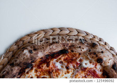 Close up view of a margherita pizza with crispy crust on woven mat Close up view of a margherita pizza with crispy crust on woven mat 125496092