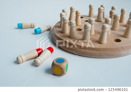 Wooden board game with pegs and colorful dice on white surface 125496101