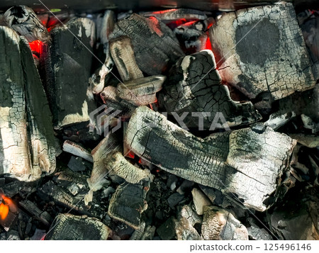 Glowing charcoal embers with cracked texture and red heat 125496146
