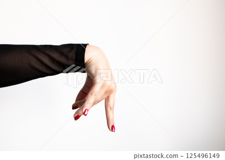 Female hand with black sleeve and red nails gesturing against white background 125496149