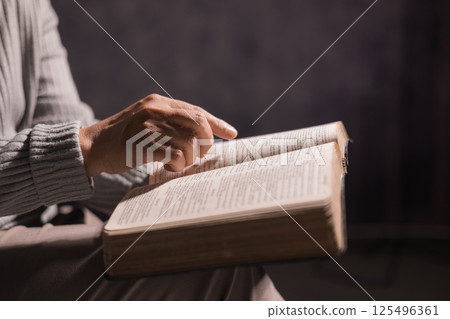 Person held the Bible in their hand, praying with deep spirituality, seeking guidance from Jesus Christ, and embracing the holy teachings of Christianity through prayer and devotion in the church. 125496361