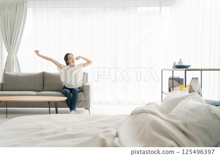 一個女人坐在沙發上和放鬆 一個女人坐在沙發上和放鬆 125496397