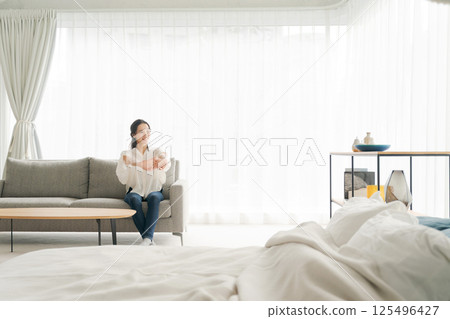 A woman sitting on a sofa and relaxing A woman sitting on a sofa and relaxing 125496427