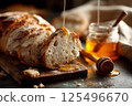 Sliced artisan bread with golden honey drizzle, captured in a rustic, cozy bakery setting. 125496670