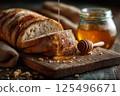 Sliced artisan bread with golden honey drizzle, captured in a rustic, cozy bakery setting. 125496671