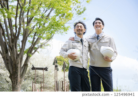 一名工人穿著工作服（例如建築管理）的圖像，背景是新鮮的綠色植物，整個身體抬頭，雙臂環抱肩膀，展望未來 125496941