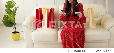 Banner Shopping with phone and card in hand sitting on sofa. Concept of e-commerce and modern consumer behavior. Copy space Banner Shopping with phone and card in hand sitting on sofa. Concept of e-commerce and modern consumer behavior. Copy space 125497162
