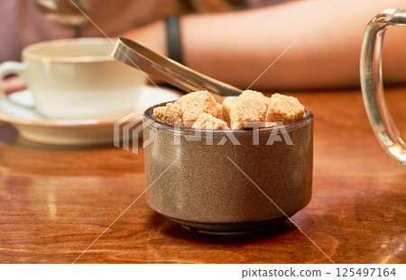 A cup of brown sugar on a wooden table in a cafe. Close up. A cup of brown sugar on a wooden table in a cafe. Close up. 125497164