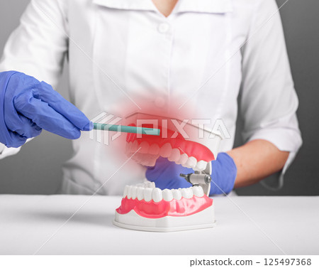 Gum inflammation. Woman pointing to mouth with red painful gingiva, showing dental disease, bleeding 125497368