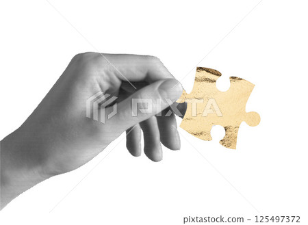 Hand holding one puzzle piece. Golden jigsaw element symbolizing idea, finance, business investment, 125497372