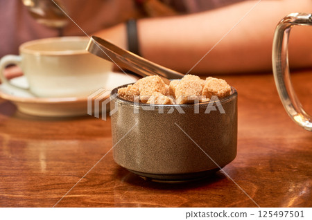 A cup of brown sugar on a wooden table in a cafe. Close up. A cup of brown sugar on a wooden table in a cafe. Close up. 125497501