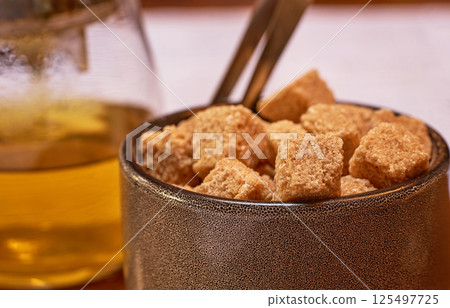 Brown cane sugar in a cup on a wooden table. Selective focus. Brown cane sugar in a cup on a wooden table. Selective focus. 125497725