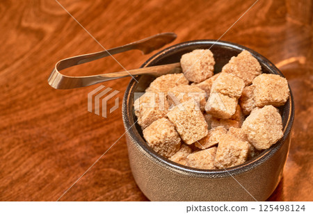 Brown cane sugar in a cup on a wooden table. Selective focus. Brown cane sugar in a cup on a wooden table. Selective focus. 125498124