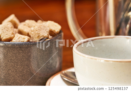 Coffee cup and cup with brown sugar on a wooden table. Soft focus. 125498137