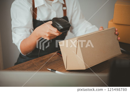Delivery staff scanning cardboard box with barcode scanner to check products for customers Delivery staff scanning cardboard box with barcode scanner to check products for customers 125498780