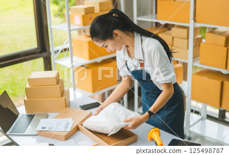 Online small business owners are packing their ordered products that customers order online into a box .concept of online shopping 125498787