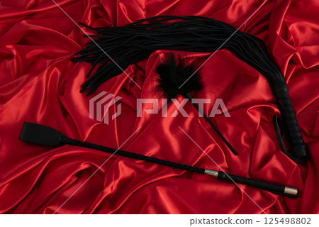 Adult sex games. Kinky lifestyle. Spank and whip ridding crop on the red linen. Bdsm outfit Adult sex games. Kinky lifestyle. Spank and whip ridding crop on the red linen. Bdsm outfit 125498802