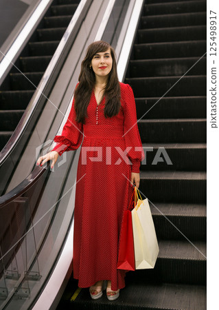 Happy woman with shopping bags on escalator. Shopping mall lifestyle and sales concept. Happy woman with shopping bags on escalator. Shopping mall lifestyle and sales concept. 125498917