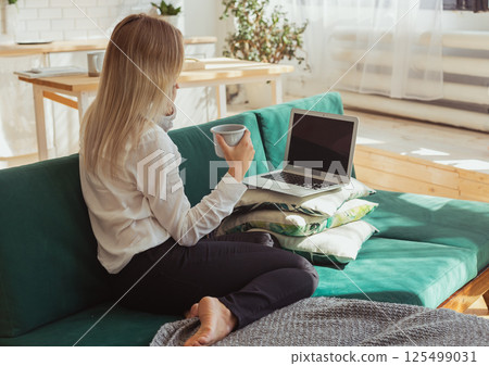 Woman talking on smartphone while working remotely. Communication, freelance and modern home lifestyle theme. 125499031