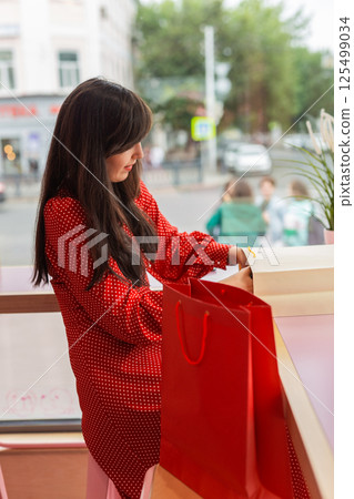 Woman exploring purchases in colorful shopping bags. Concept of consumption and lifestyle leisure 125499034
