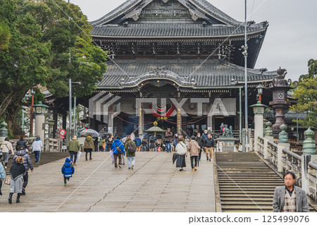 People heading to the shrine for the first time in the New Year in the rain and the main hall of Toyokawa Inari Shrine (Aichi Prefecture) 125499076