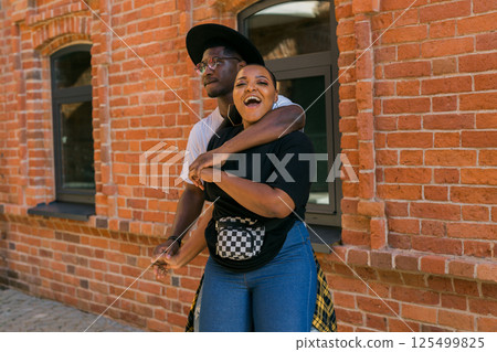 Happy african american couple laughing and hugging in the city street. Concept of love, friendship, fun, happiness and relationships. Copy space 125499825