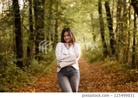 Young Woman Smiling in Autumn Forest Path Young Woman Smiling in Autumn Forest Path 125499831