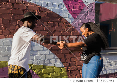 African american couple dancing together outdoors near colorful wall. Concept of love, joy, movement and urban lifestyle. Bachata, salsa, kizomba or merengue dance African american couple dancing together outdoors near colorful wall. Concept of love, joy, movement and urban lifestyle. Bachata, salsa, kizomba or merengue dance 125499863
