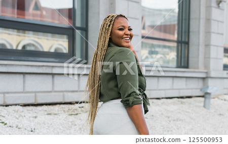 African american smiling woman looking back in the city streets. Joy, confidence, and positive emotions in an urban environment. 125500953