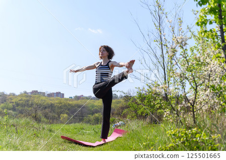 Woman practicing extended hand to big toe pose outdoors with city view. Woman practicing extended hand to big toe pose outdoors with city view. 125501665