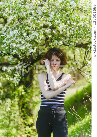 Woman enjoying springtime standing under blooming tree. Woman enjoying springtime standing under blooming tree. 125501669